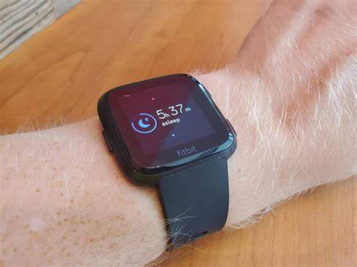 A man wearing a Fitbit Sense navigates his watch face selections