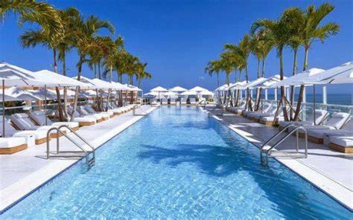 A resort with white beach chairs, white umbrellas, and white flowering trees
