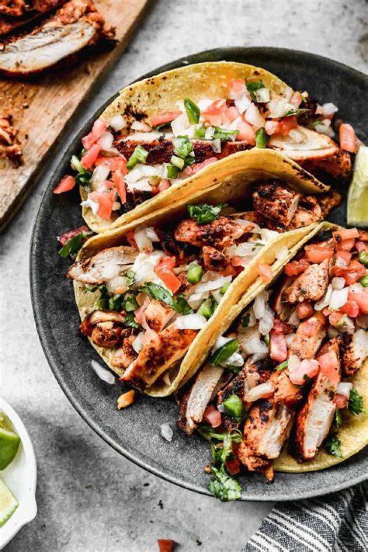 A table covered in tacos, lime slices, and drinks