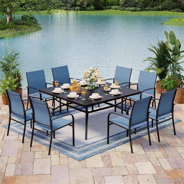 An outdoor dining table topped with food, wine, and candles