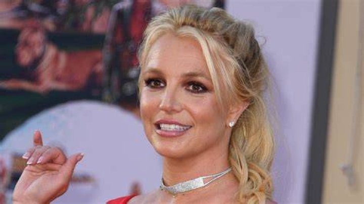 Britney Spears waving and smiling in a red dress