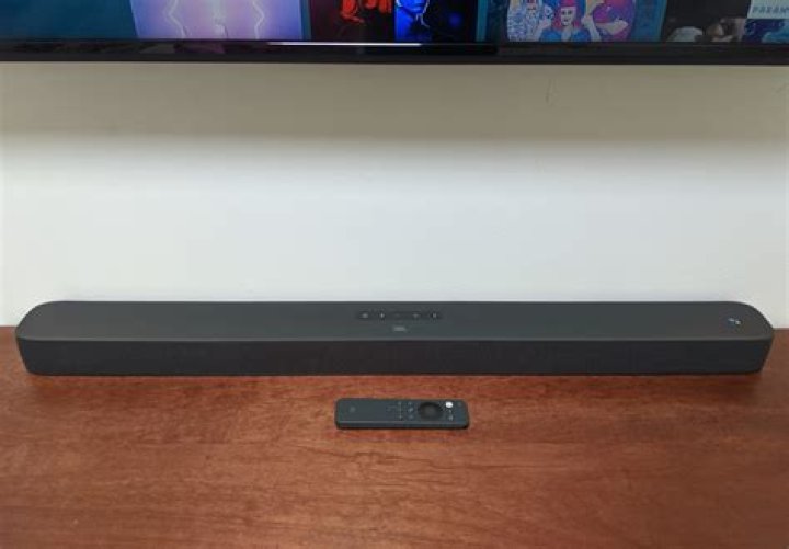 JBL Link Bar 1 Woman holding remote Google Assistant JBL Link Bar review: A woman holding the JBL Link Bar remote and speaking to Google Assistant to switch songs on Spotify.