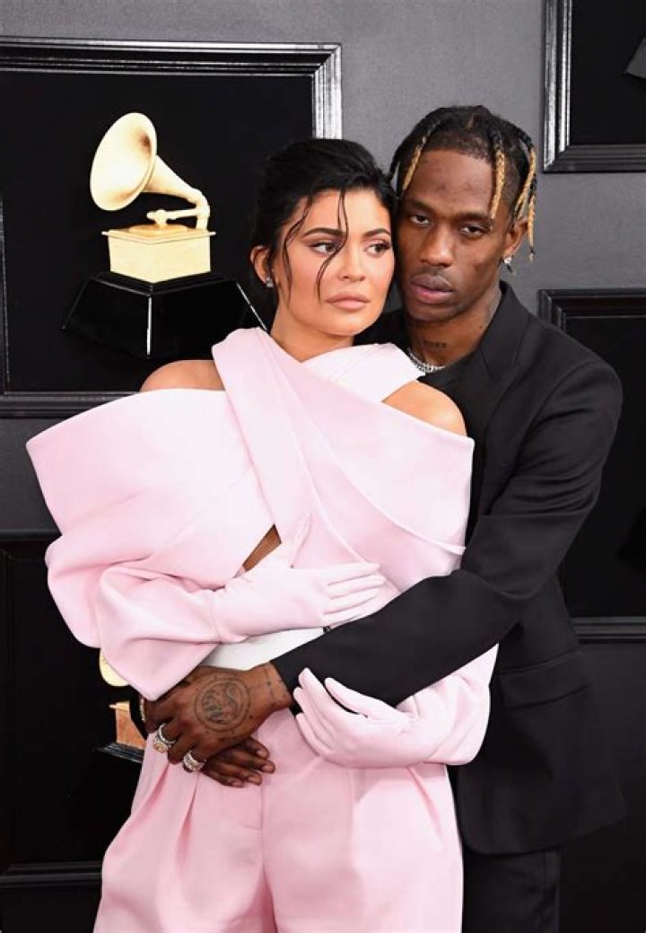 Kylie Jenner and Travis Scott hugging on a beach at sunset.
