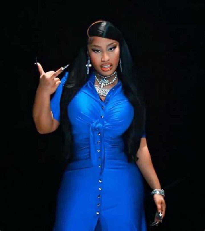 Nicki Minaj in a blue outfit wearing a diamond necklace and diamond earrings (left), Nicki Minaj performing live in a white outfit near male models in Trojan attire (right)