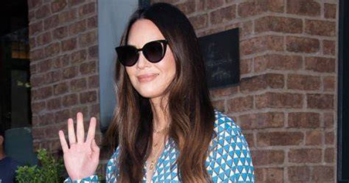 Olivia Munn smiles and waves to paparazzi